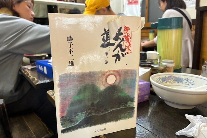 A menu with Japanese characters and a painting of a landscape. 5