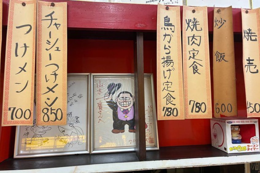 A food stall with various signs indicating prices for different dishes. 4