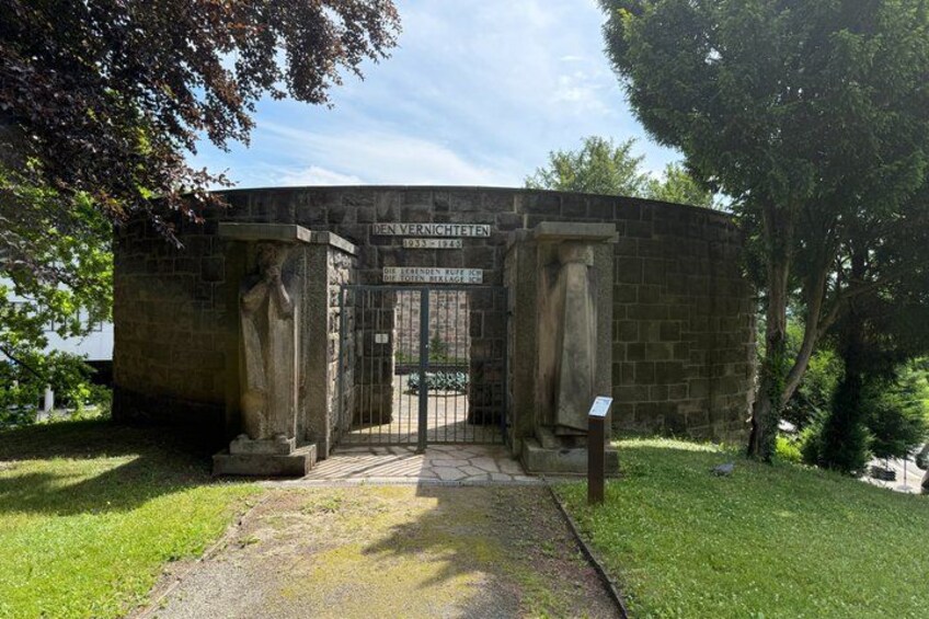 A stone structure with a sign reading 'Vernichteten 1933-1945' and a plaque below. 2