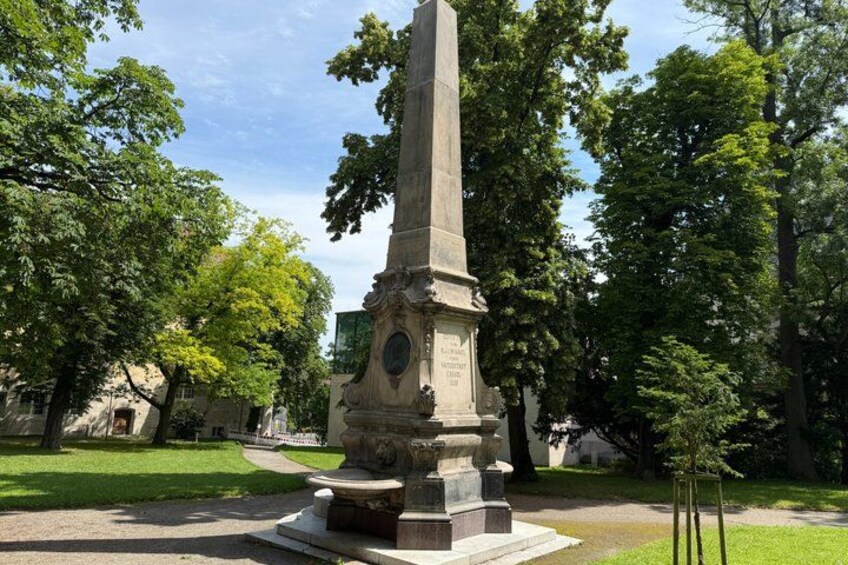 A tall, ornate monument with inscriptions, surrounded by lush green trees and a well-maintained lawn. 4