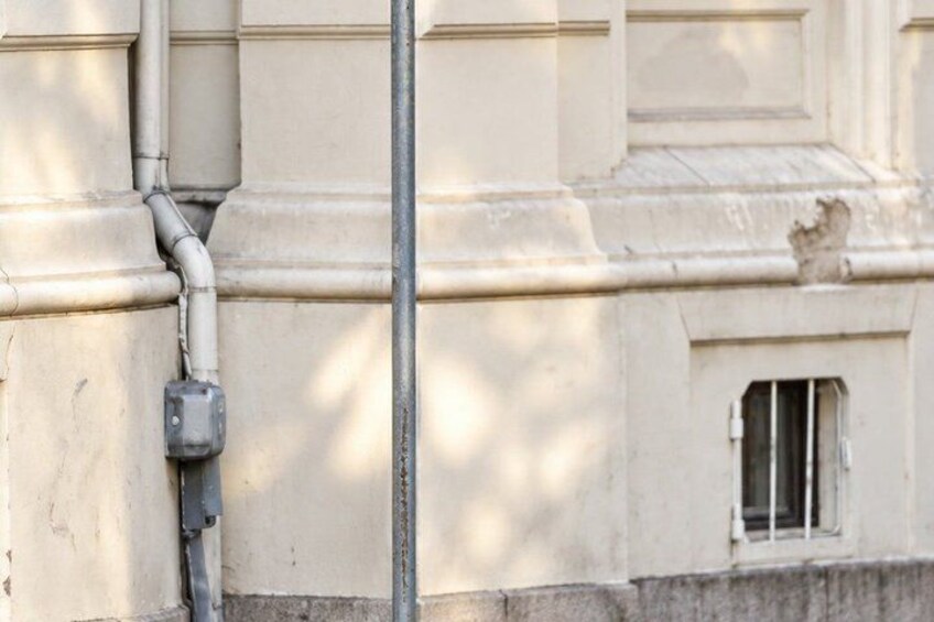 A building facade with a window, a utility box, and a vertical pipe. 2