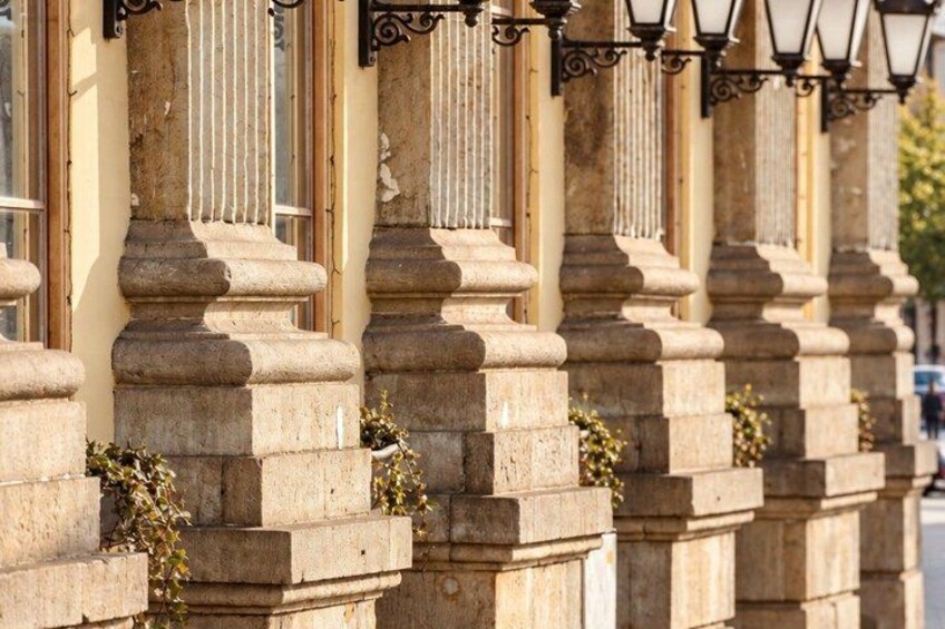 A row of stone buildings with ornate window frames and decorative columns. 5