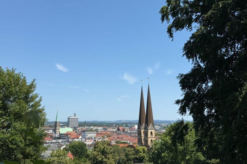 A cityscape with a prominent church spire, a green-roofed building, and a clear blue sky. 4