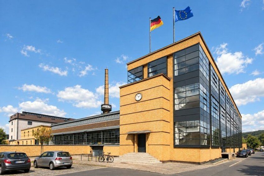 A building with a clock, flags, and parked cars. 3