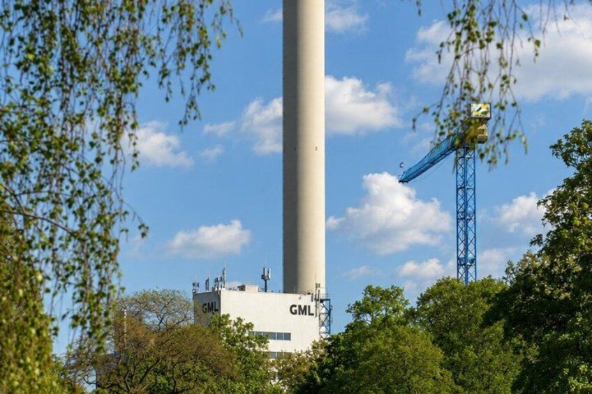 A tall white tower with 'GML' written on it, surrounded by trees and a blue crane. 2