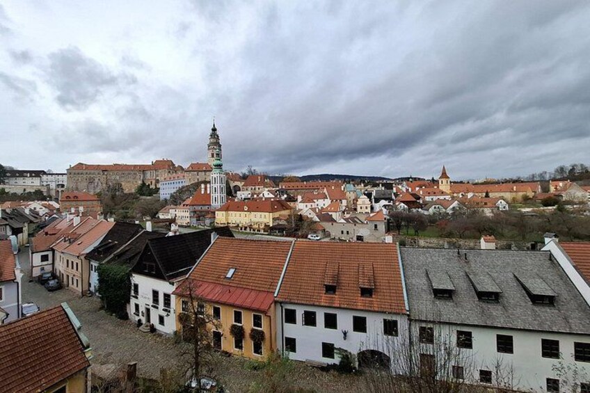 A town with historic buildings, a prominent church tower, and a castle in the background. 5