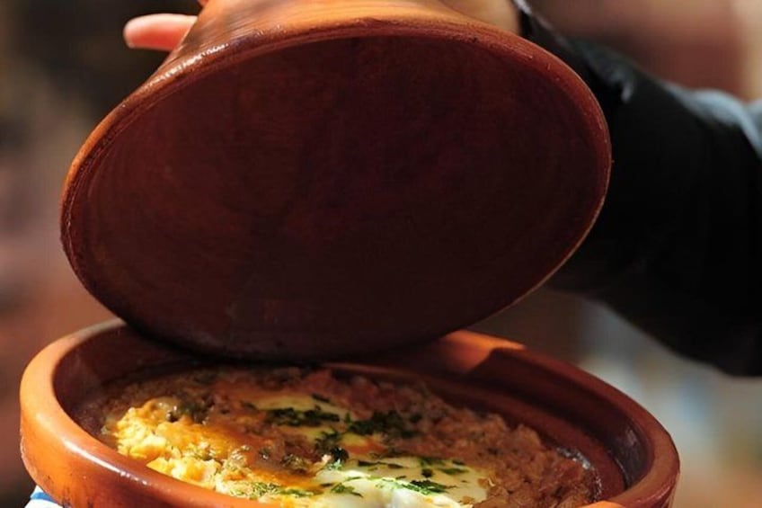 A person holding a clay pot over a dish. 5