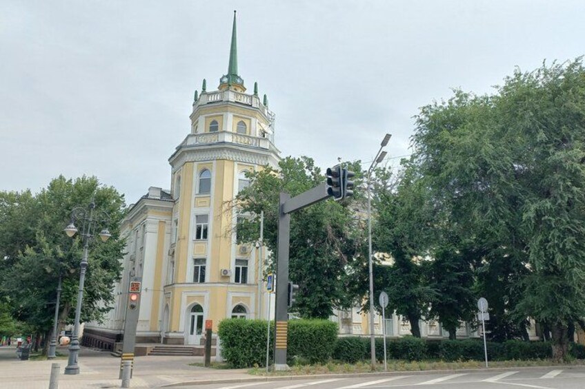 A historic building with a green spire, traffic lights, and trees. 5