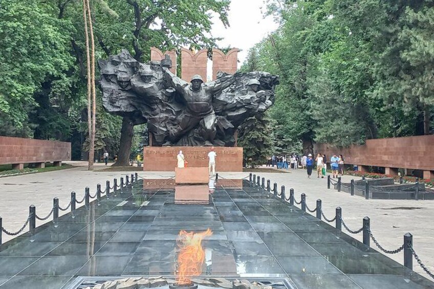 A memorial with a central sculpture, a reflective water feature, and a paved walkway. 3