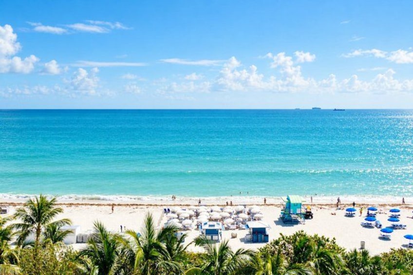 A beach with clear turquoise water, white sand, and palm trees. 2
