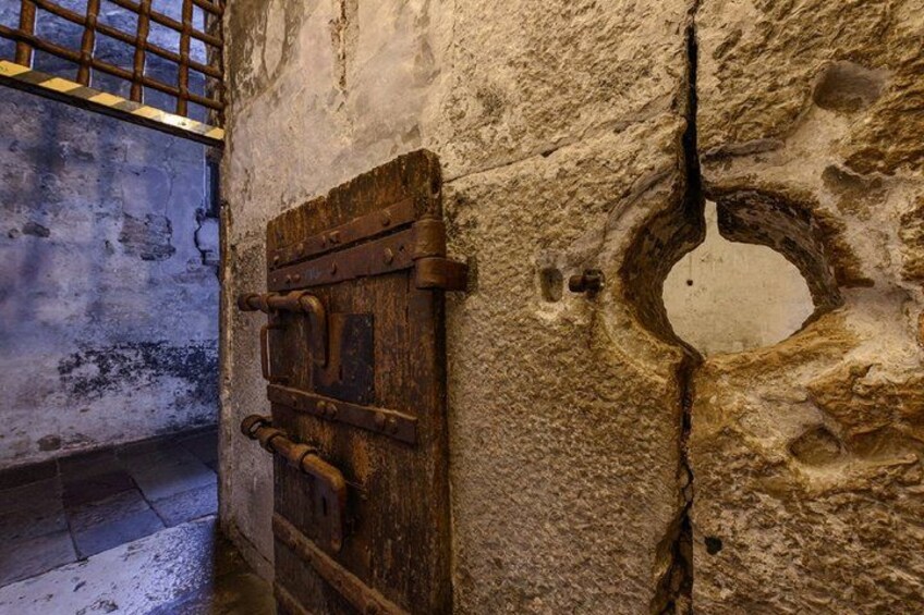A stone wall with a wooden door and a circular window. 5