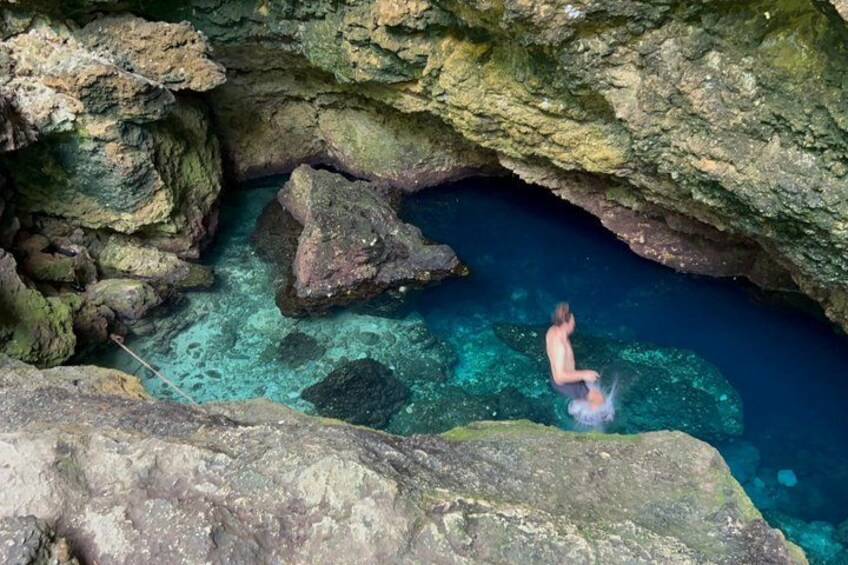 A person swimming in a clear blue pool surrounded by rocky terrain. 5