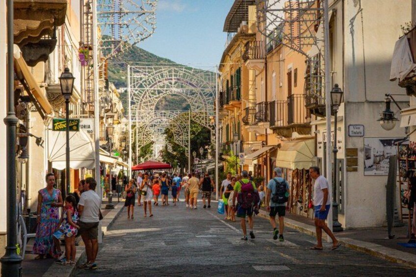 A bustling street with people walking, a Ferris wheel, and buildings with balconies. 3