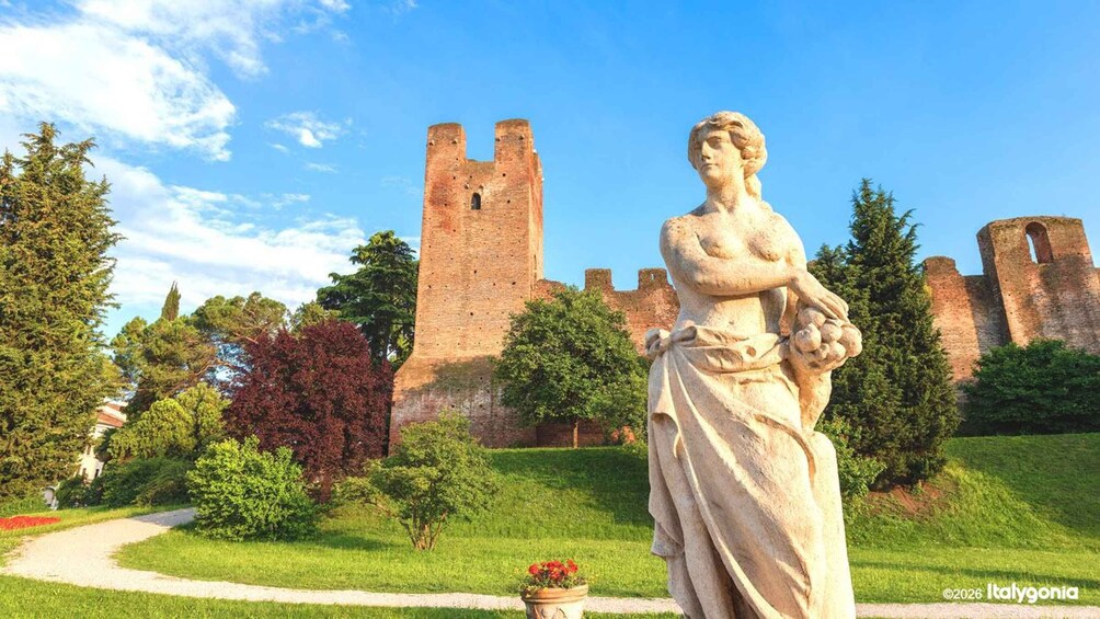Eine Statue in einem Garten, im Hintergrund ein Schloss. 3