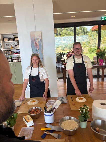 Deux personnes portant des tabliers, debout devant une table sur laquelle se trouvent des ingrédients et des ustensiles de cuisine. 2