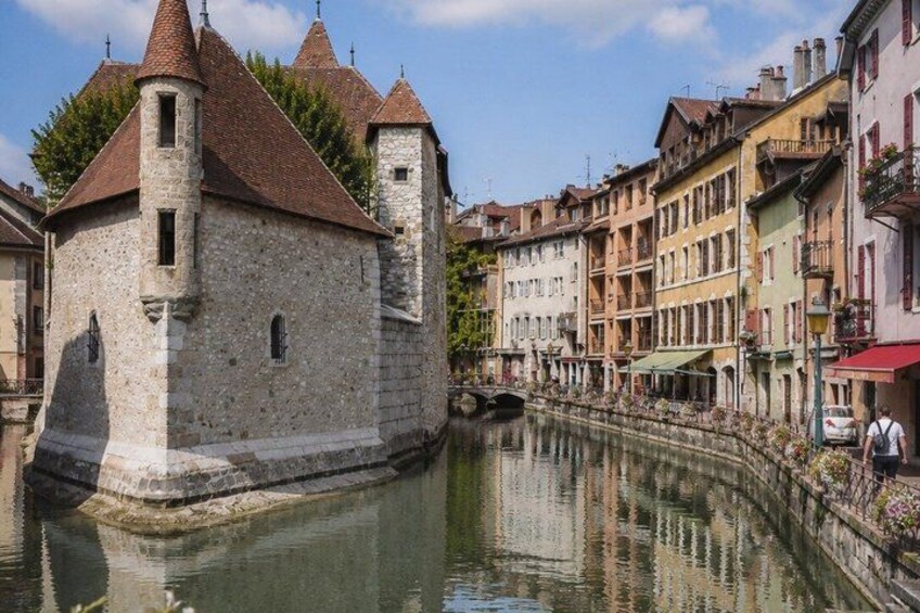 A historic stone tower, a narrow canal, and colorful buildings along the water's edge. 3