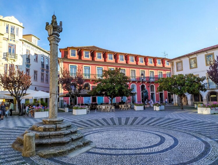 A cobblestone plaza with a fountain, surrounded by colorful buildings and outdoor seating. 3