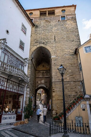 A stone archway in a narrow street with shops on either side. 1