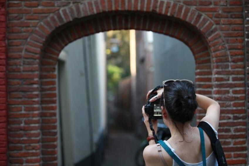 A person taking a photo through a brick archway. 5