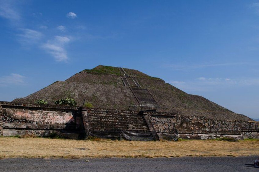 A large pyramid with a staircase leading to the top, surrounded by a stone wall. 3