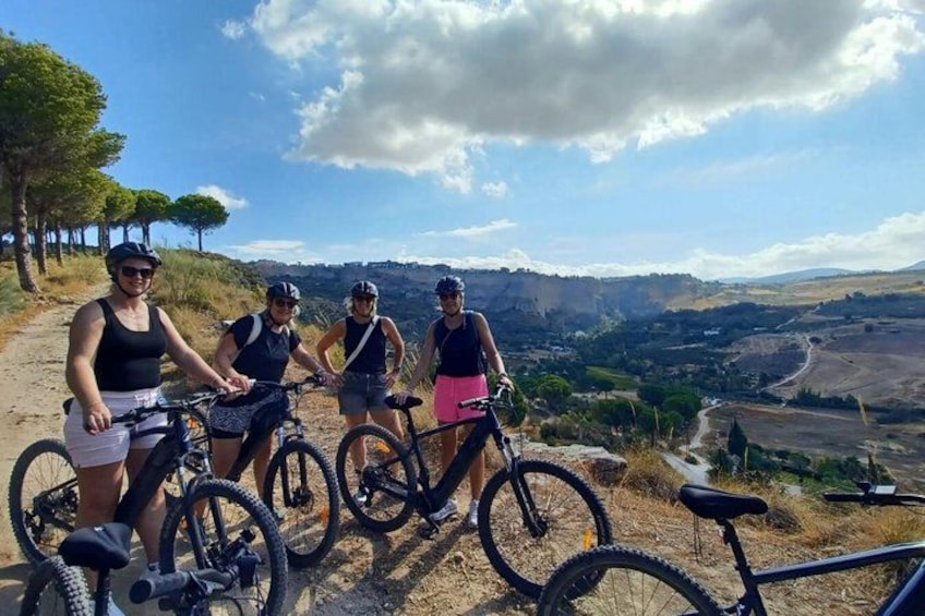 A group of cyclists on a dirt path with a scenic view of hills and trees. 4