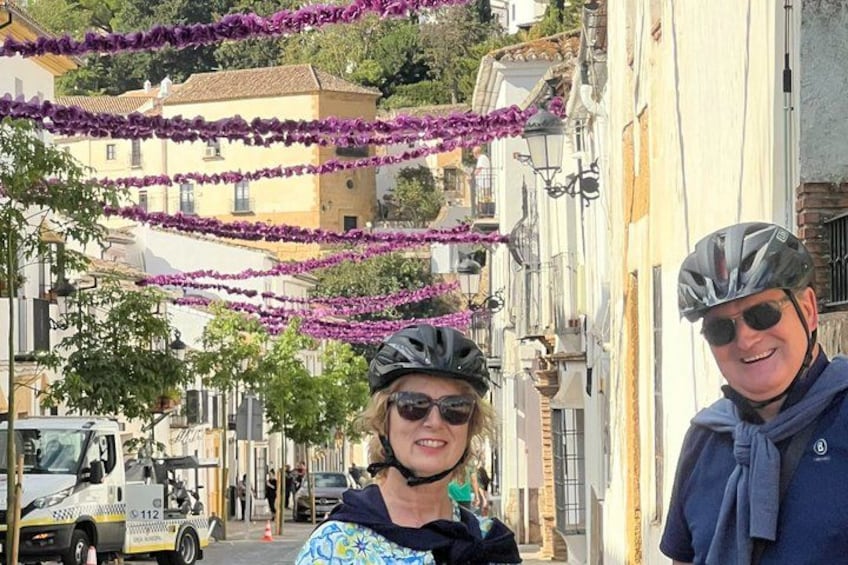 A street lined with buildings and purple flowers. 3