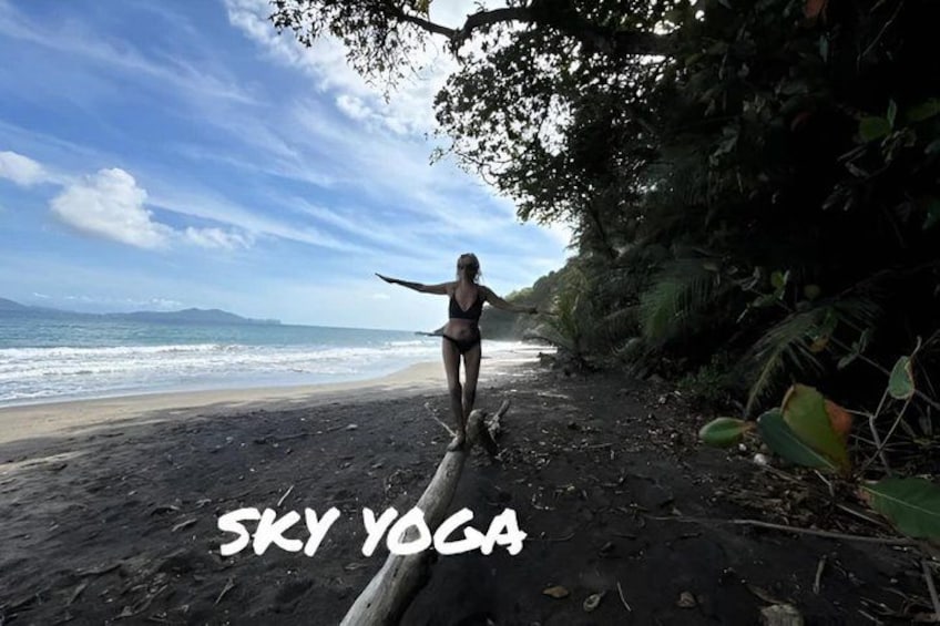 A person practicing yoga on a beach with a view of the ocean and a clear sky. 1