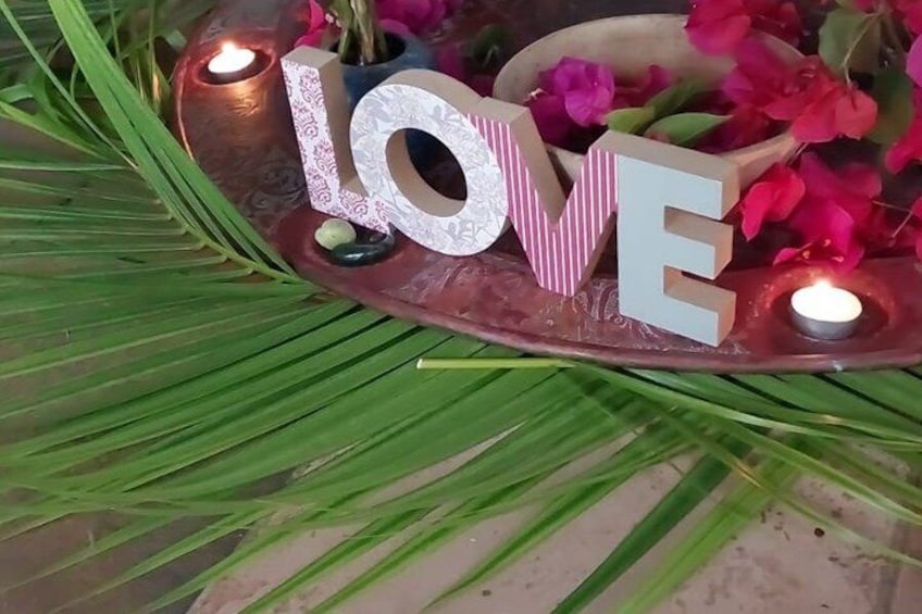 A decorative setup with the word 'LOVE' spelled out in letters, surrounded by candles and flowers on a tray. 3
