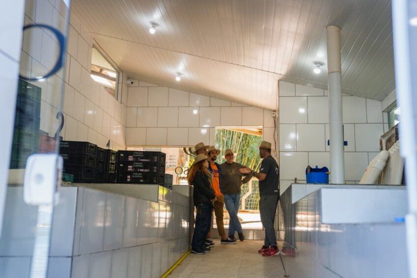 A group of people in a tiled room with a white ceiling and a glass partition. 3