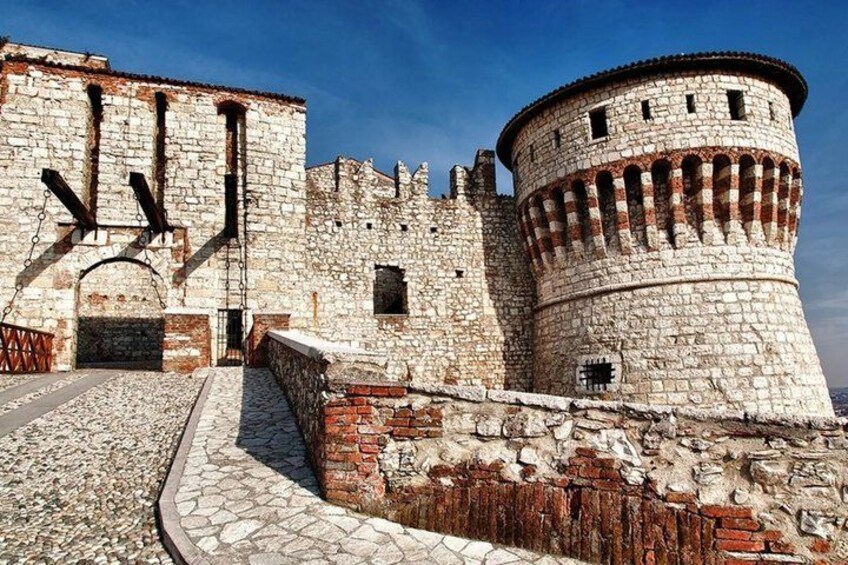 A historic stone fortress with a round tower and a large arched entrance. 3