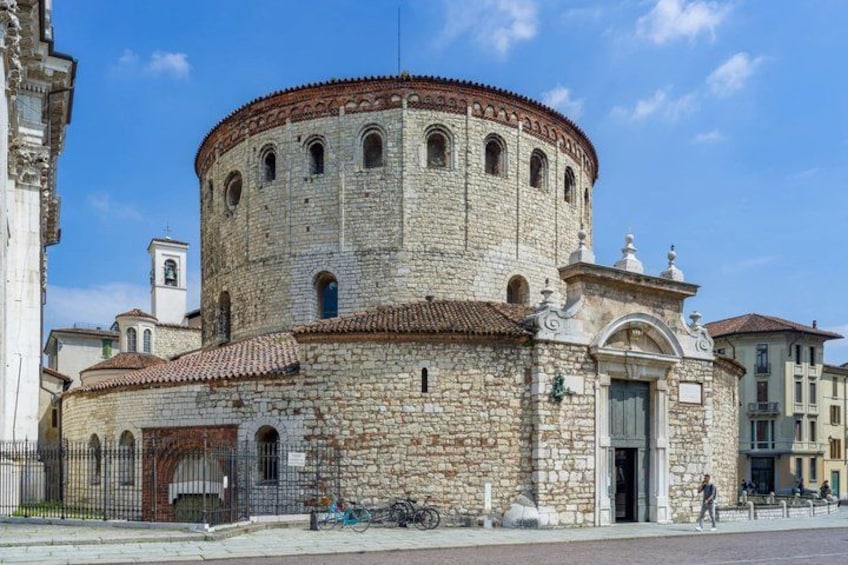 A historic stone building with a round tower, arched windows, and a tiled roof. 1