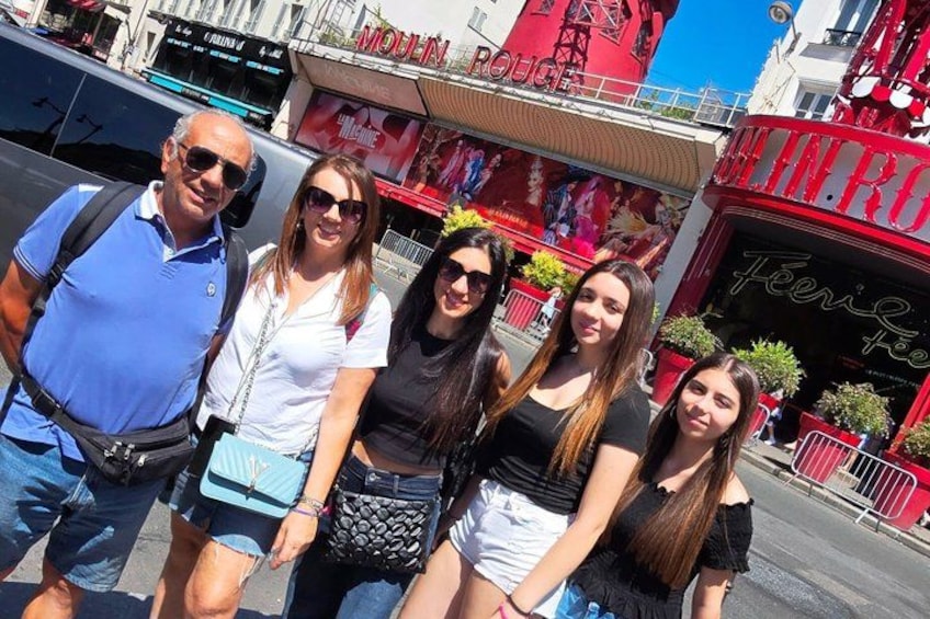 A group of people standing in front of a red building with the sign 'Moulin Rouge.' 3