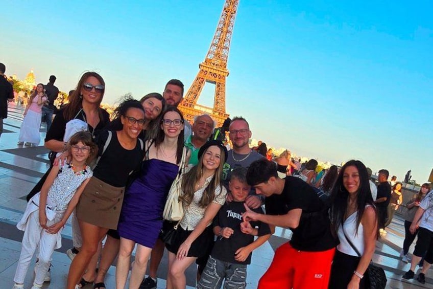 A group of people posing in front of the Eiffel Tower. 4