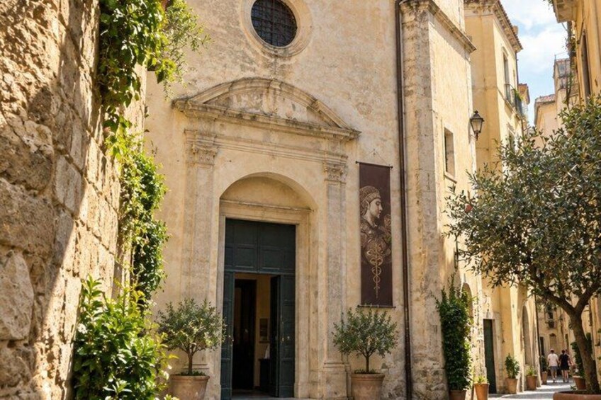 A historic building with a round window, a door, and a mural. 2