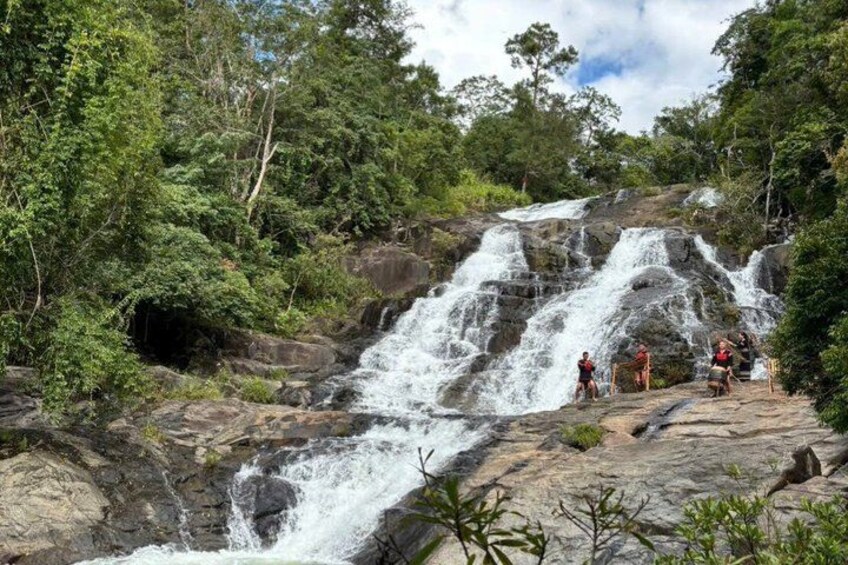 A waterfall cascading over rocks surrounded by dense greenery. 3