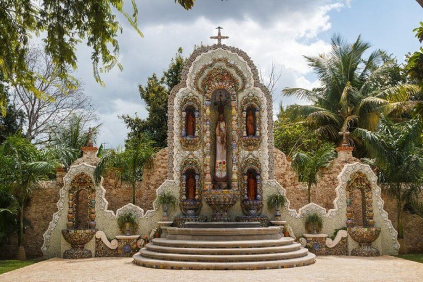 A church with a cross, surrounded by palm trees and a stone wall. 3