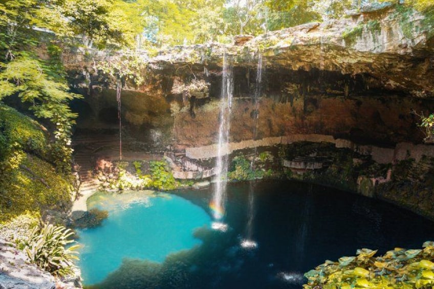 A waterfall cascading into a clear blue pool surrounded by lush greenery and rocky cliffs. 2