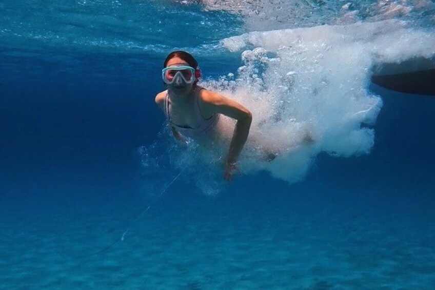 A person swimming underwater in clear blue water. 2