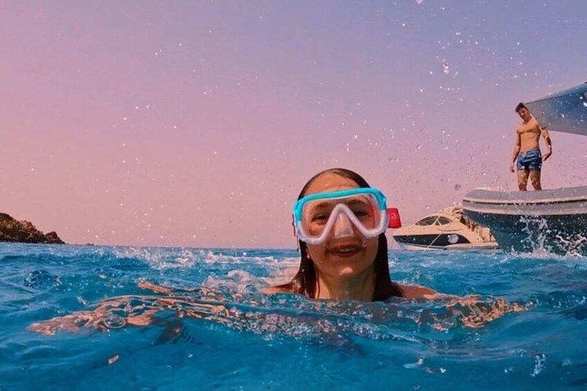 A person swimming in a pool with a boat and another person standing on a dock in the background. 3