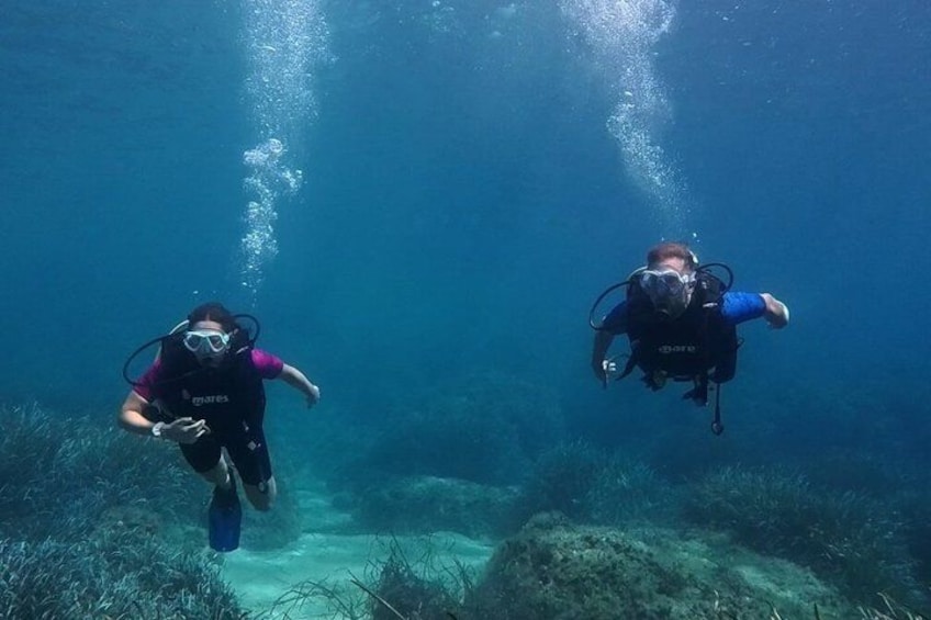 Two scuba divers underwater with bubbles rising to the surface. 1