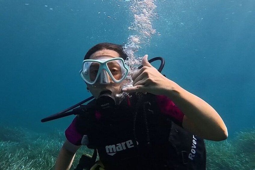 A person underwater, wearing a scuba diving mask and a black vest with the word 'mare' on it. 4