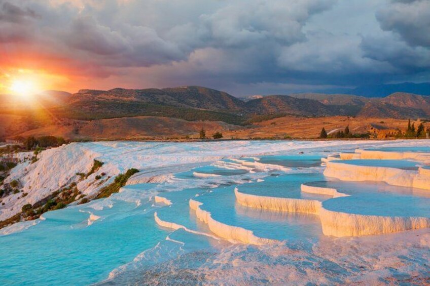 Terraced mineral pools, a sunset, and a mountainous landscape. 2