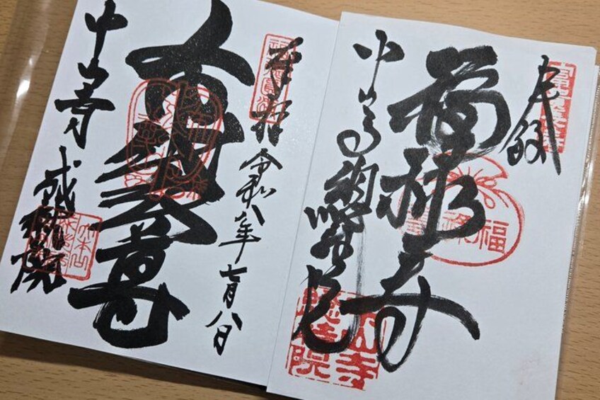 A book with Japanese calligraphy on white pages with red stamps. 1