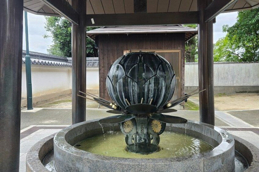 A traditional Japanese water fountain with a large stone basin and a decorative stone structure in the center. 2