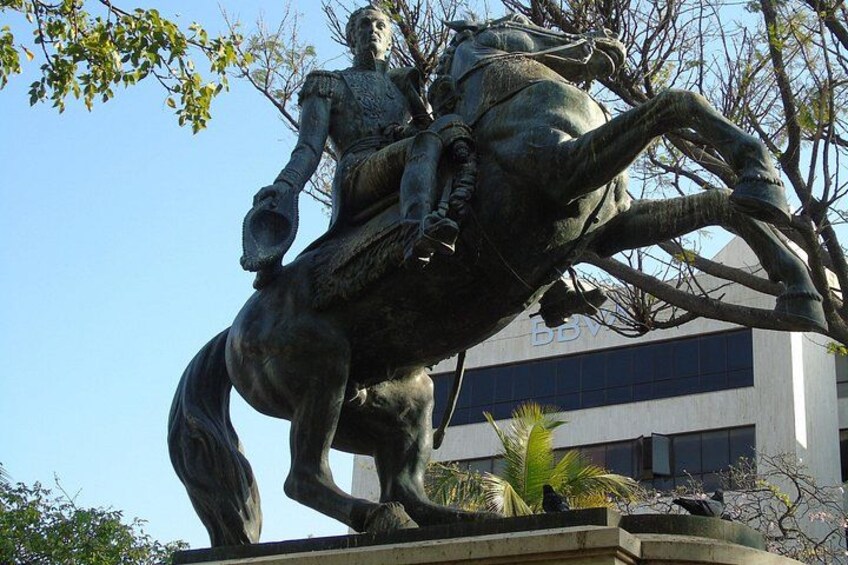 A statue of a man on horseback, a building in the background, and some trees. 2