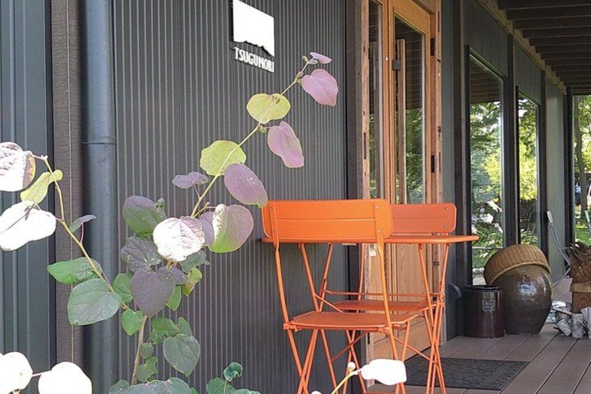 A building with a corrugated metal exterior, a wooden door, and an orange folding chair outside. 3