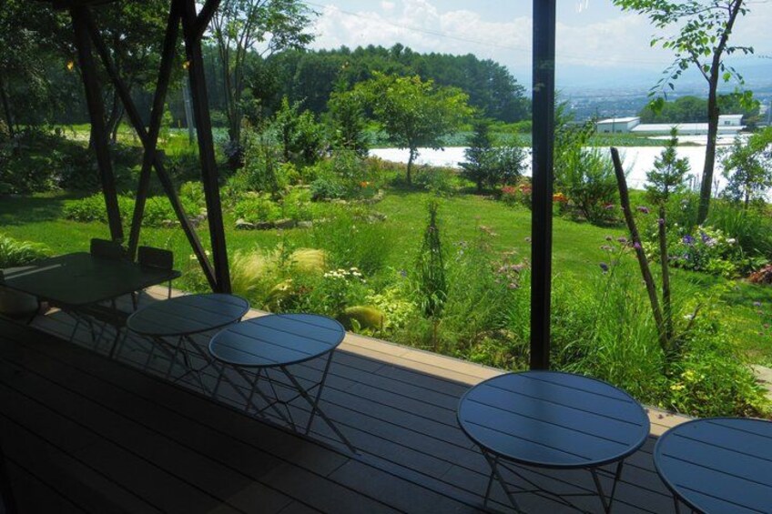 A deck with outdoor seating overlooking a lush garden and a lake. 2