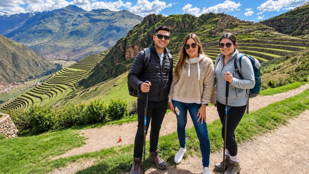 Eine Gruppe Wanderer auf einem Pfad mit terrassenförmig angelegten Feldern und Bergen im Hintergrund. 4