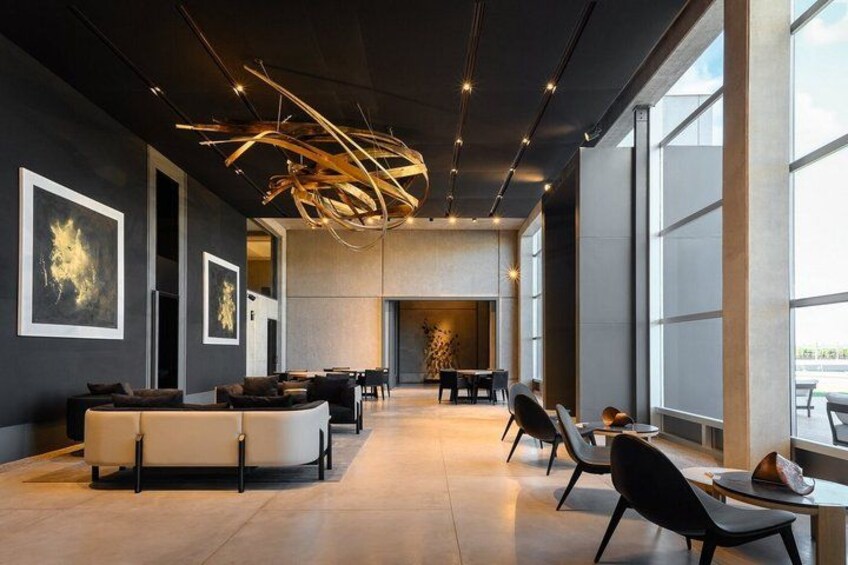 A modern interior with a curved sofa, black chairs, and a unique ceiling light fixture. 5