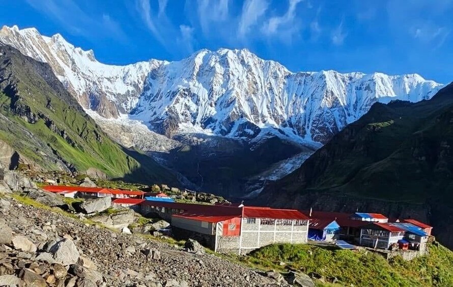 Un paysage montagneux aux sommets enneigés, une vallée parsemée de bâtiments et un ciel bleu dégagé. 5